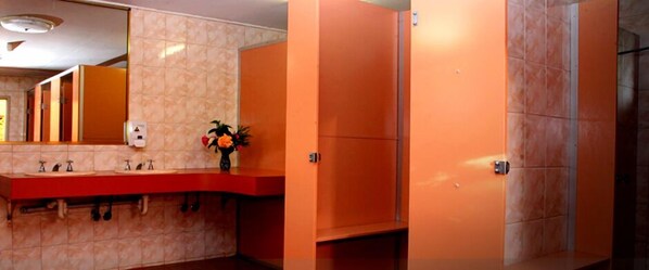 Un baño con un lavamanos rojo, un espejo y armarios naranja.