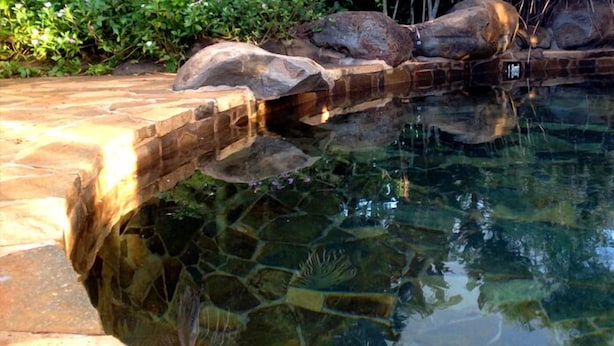 A clear pool with a stone edge and rocks in the background. - Atherton Holiday Park (Atherton)