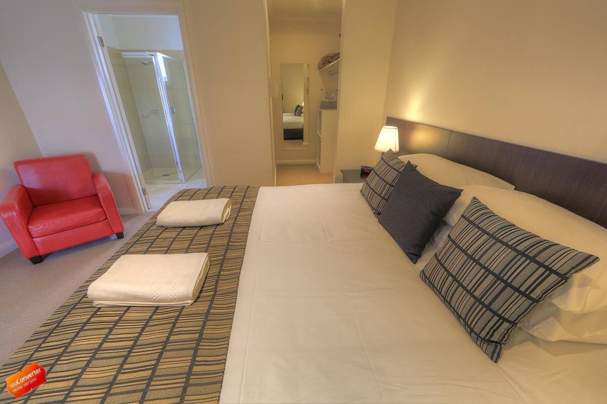 A hotel room with a large bed, a red armchair, and a walk-in closet.