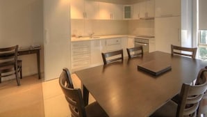 A modern kitchen with white cabinets, a dining table with chairs, and a window providing natural light.