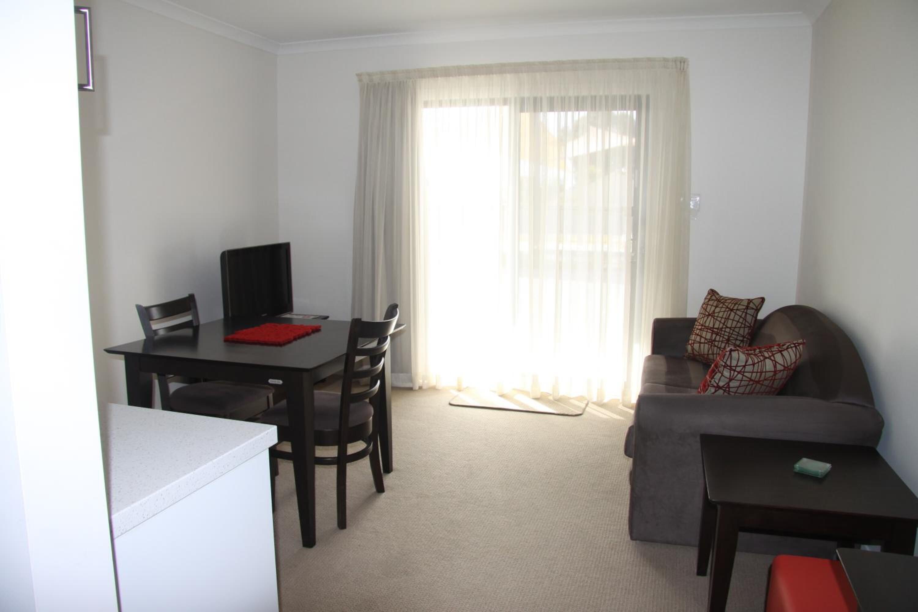 A compact living space with a dining table, chairs, a sofa, and a small coffee table.