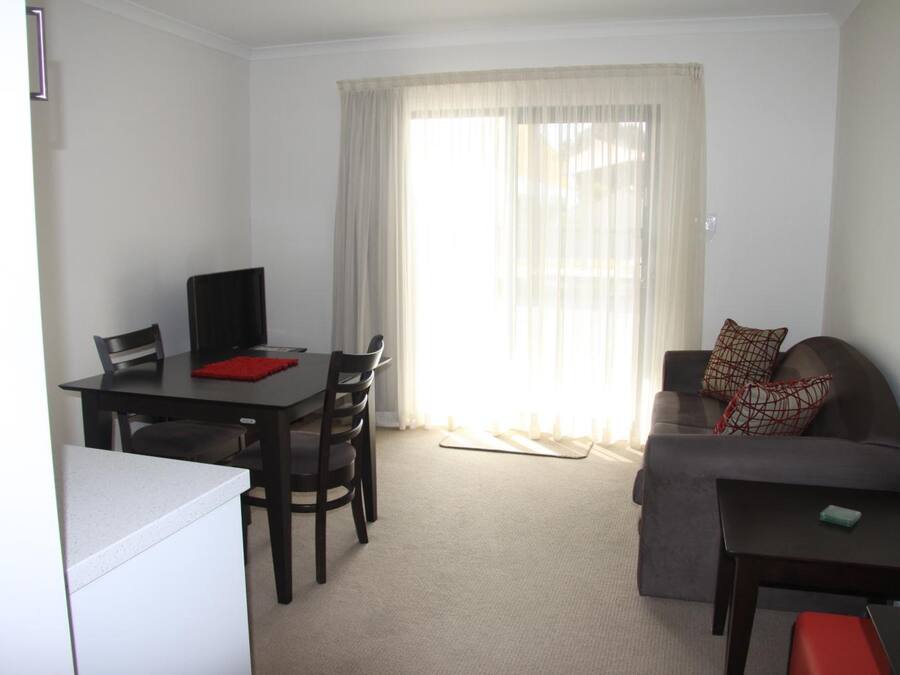 A compact living space with a dining table, chairs, a sofa, and a small coffee table.