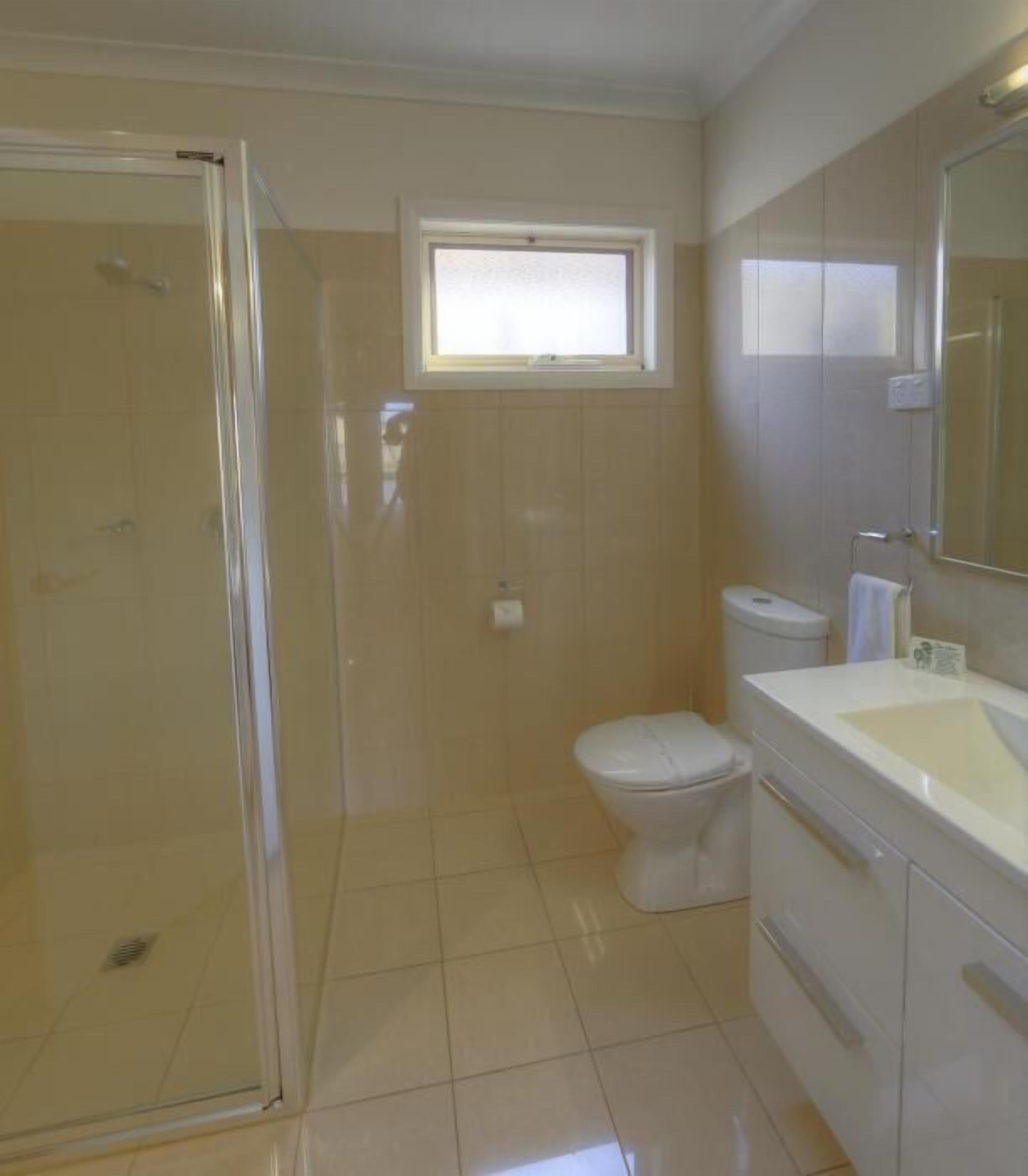 Une salle de bain avec douche, toilettes et lavabo.