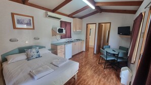 A room with a bed, a small kitchenette, a dining table, and a TV. - Goondiwindi Tourist Park (Goondiwindi)