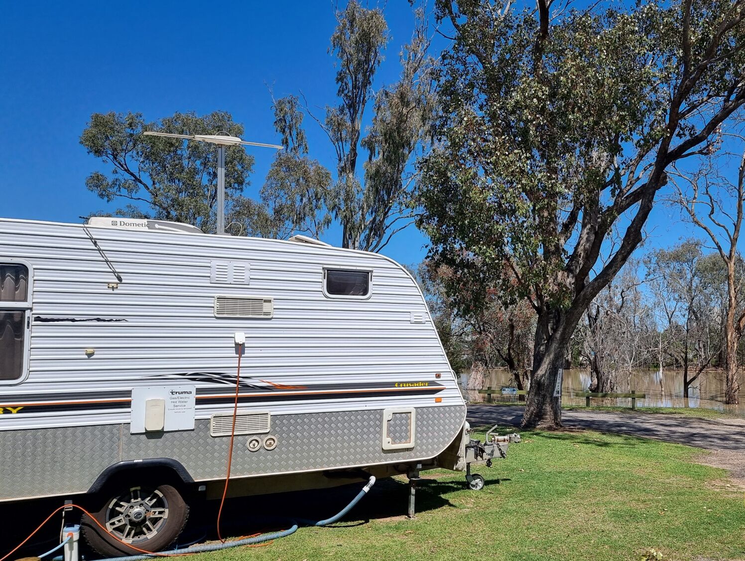 A white RV with a "Dometic" sign, parked on grass with trees in the background.