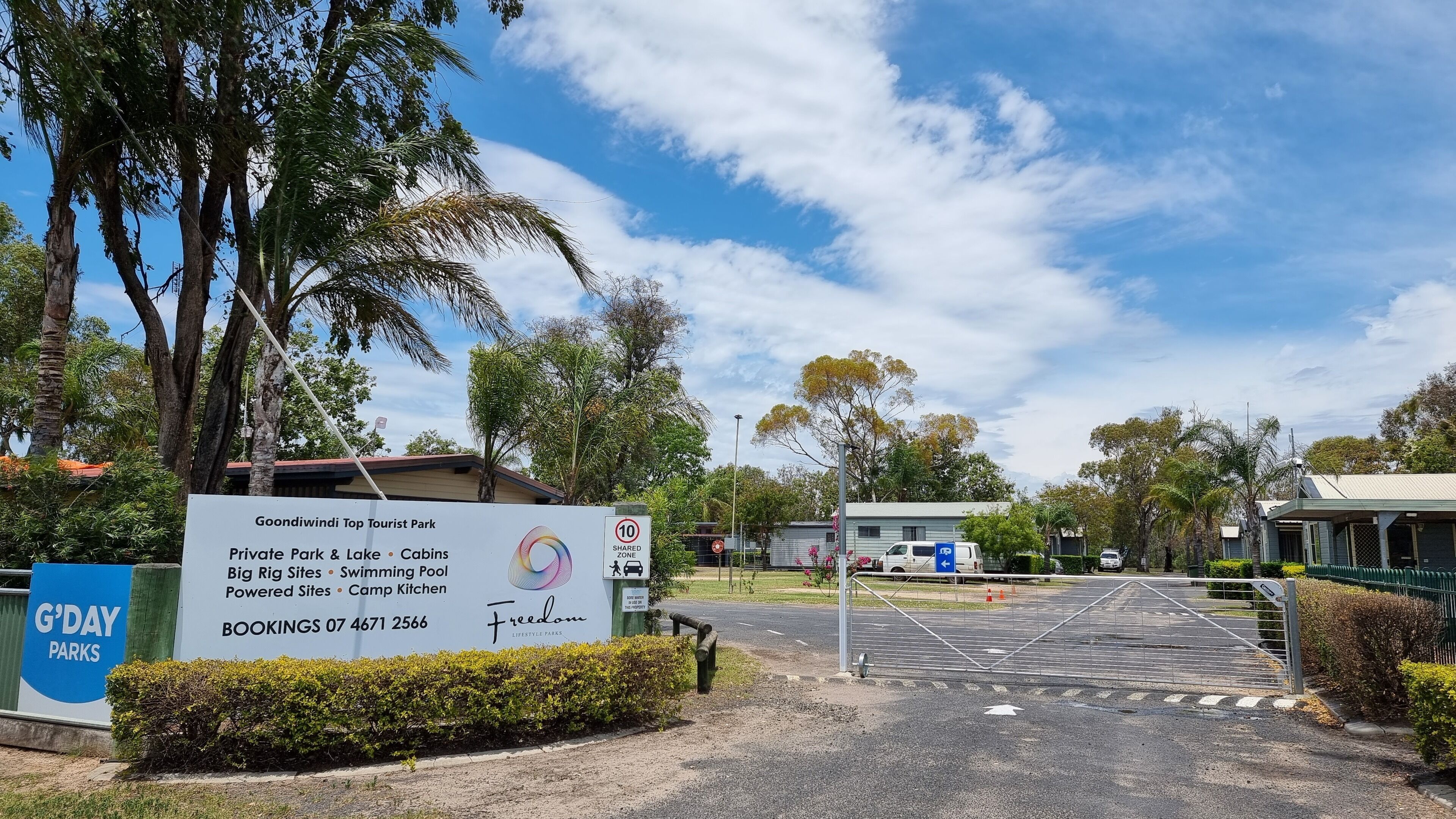 A sign for Goondiwindi Top Tourist Park with amenities like a private park, lake, cabins, big rig sites, swimming pool, powered sites, and camp kitchen.