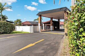 A gas station with a covered canopy, a fenced parking area, and a clear sky.