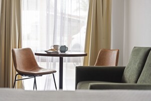 A room with a round table, two chairs, and a sofa.