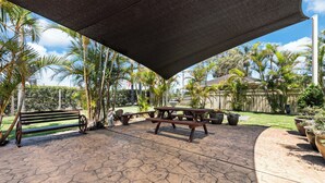 Un patio cubierto con un banco de madera, una mesa de picnic y plantas en macetas.