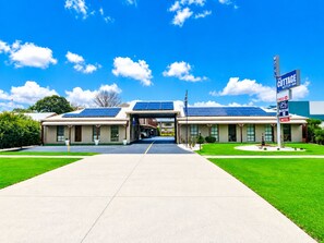 A motel with a covered entrance, solar panels on the roof, and a sign indicating it's a motor inn.