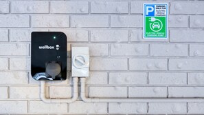 A wall-mounted wallbox and a parking sign for electric vehicle charging. - The Cottage Motor Inn Albury CBD (South Albury)