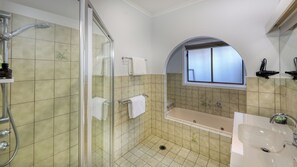 A bathroom with a glass-enclosed shower, a freestanding bathtub, and a sink.