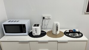 A kitchenette with a microwave, toaster, kettle, and a tray with tea bags. - The Cottage Motor Inn Albury CBD (South Albury)