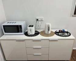 Cafetera o tetera, frigorífico grande, microondas y hervidor eléctrico