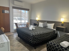 Habitación de hotel con una cama grande, dos mesitas de noche con lámparas, una silla, un escritorio y una ventana con vistas al exterior.