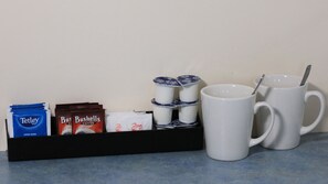 A coffee station with a coffee maker, a milk jug, a coffee packet, and a mug. - The Cottage Motor Inn Albury CBD (South Albury)