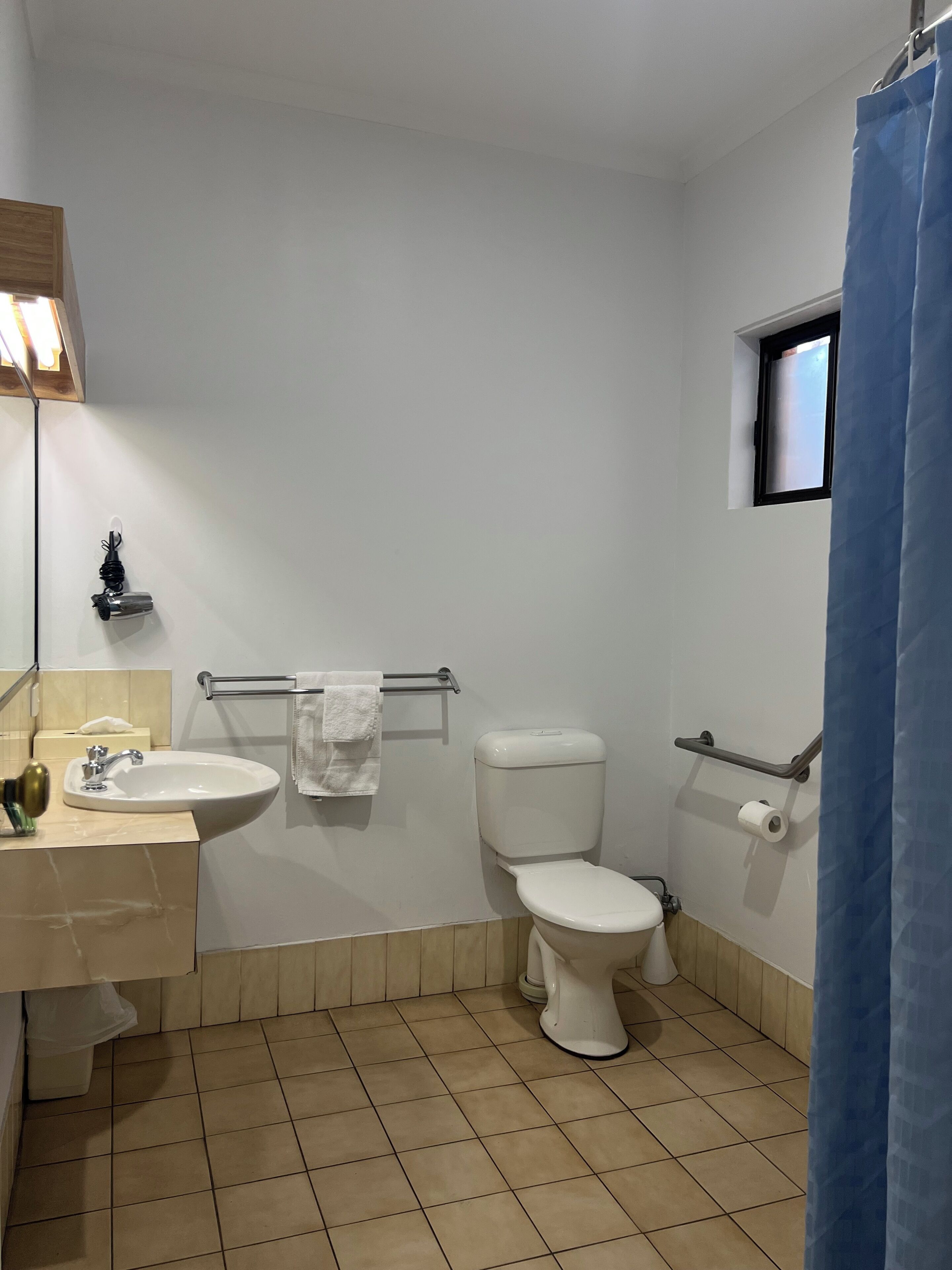Un baño con lavamanos, inodoro y una pequeña ventana.