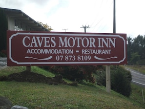 Señal para Caves Motor Inn, un alojamiento y restaurante, con un número de contacto.