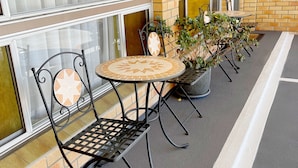 An outdoor seating area with metal chairs and a round table, surrounded by brick walls and large windows. - Squatters Homestead Motel (Casino)