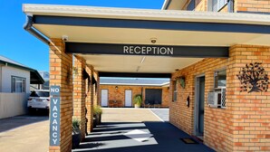 A reception area with a 'RECEPTION' sign, a 'NO VACANCY' sign, and a 'WELCOME' painted on the ground. - Squatters Homestead Motel (Casino)
