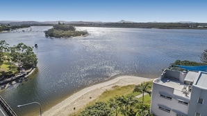 A coastal view with a beach, a bridge, and a building with balconies. - Reflections Holiday Apartments (Maroochydore)
