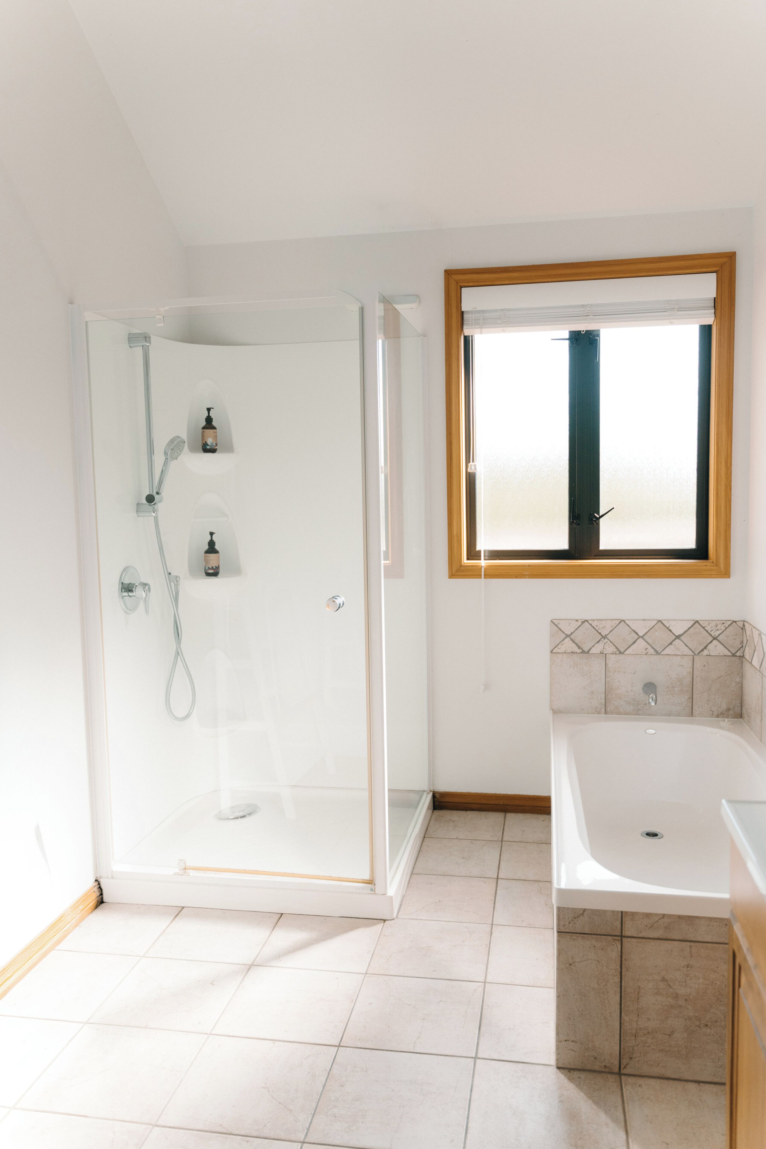 Une salle de bain avec une douche à parois de verre, une baignoire et une fenêtre au-dessus du lavabo.
