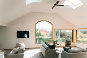 A spacious loft with a high ceiling, large windows, and a ceiling fan. - Tasman Holiday Parks – Wanaka (Wanaka)