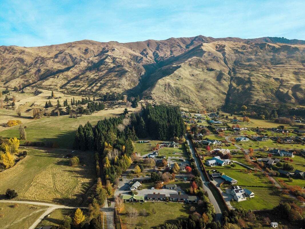 Un quartier résidentiel avec des maisons, une route et des montagnes en arrière-plan.