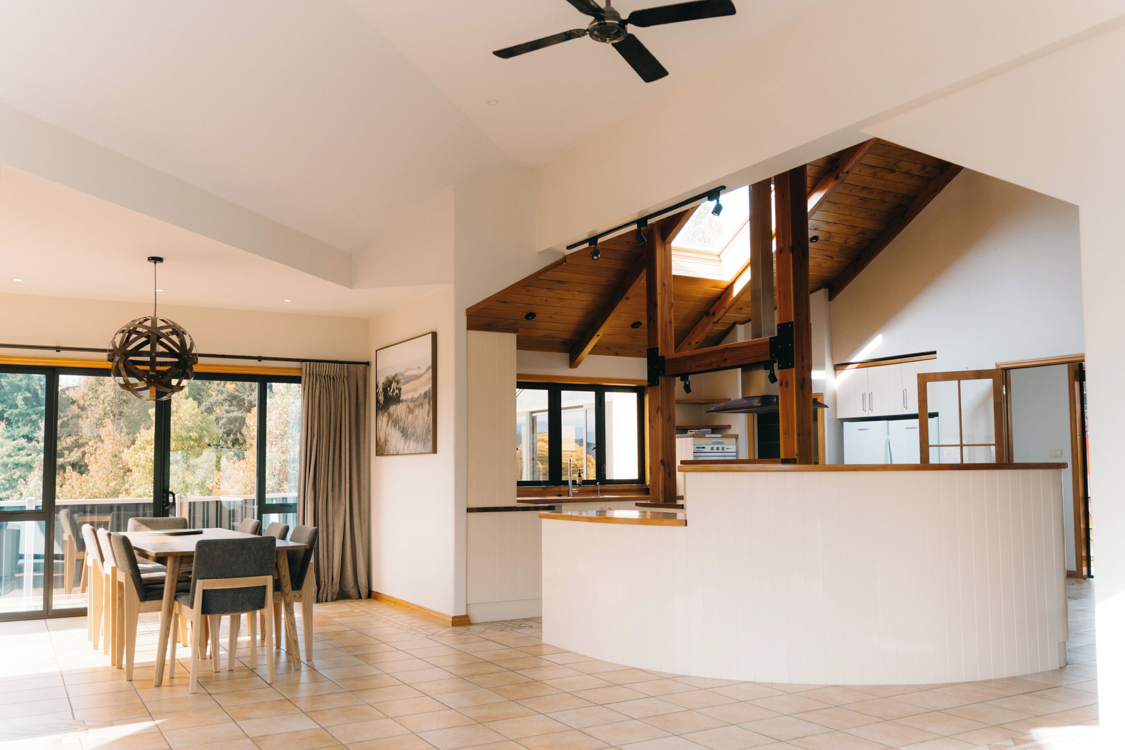A spacious kitchen with a central island, large windows, and a ceiling fan.