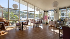 Una habitación amplia con ventanas grandes, piso de madera y una mesa con sillas.