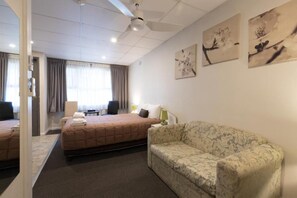 A hotel room with two beds, a sofa, a ceiling fan, and artwork on the walls. - Mittagong Motel (Mittagong)