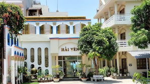 Un hotel con entrada central, varios balcones y una variedad de plantas en macetas.