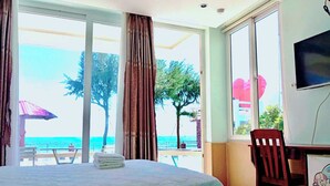 Una habitación de hotel con cama, escritorio y vista a la playa y al océano.