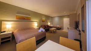 A hotel room with a large bed, a sofa, a small table, and a TV. - The Imperial Motel (Bowral)