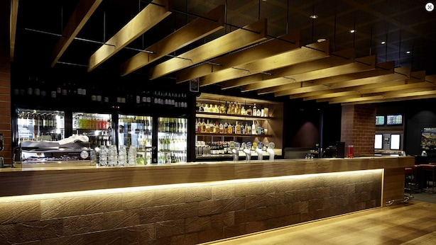 A bar area with a wooden counter and shelves stocked with bottles. - The Imperial Motel (Bowral)