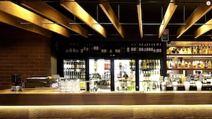 A bar with a brick wall, wooden ceiling beams, and shelves stocked with bottles. - The Imperial Motel (Bowral)