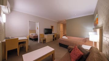 A hotel room with a bed, a desk, a television, and a couch.