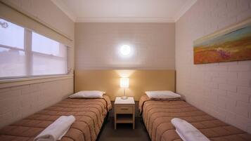 A twin room with two beds, a nightstand, a lamp, and a painting on the wall.