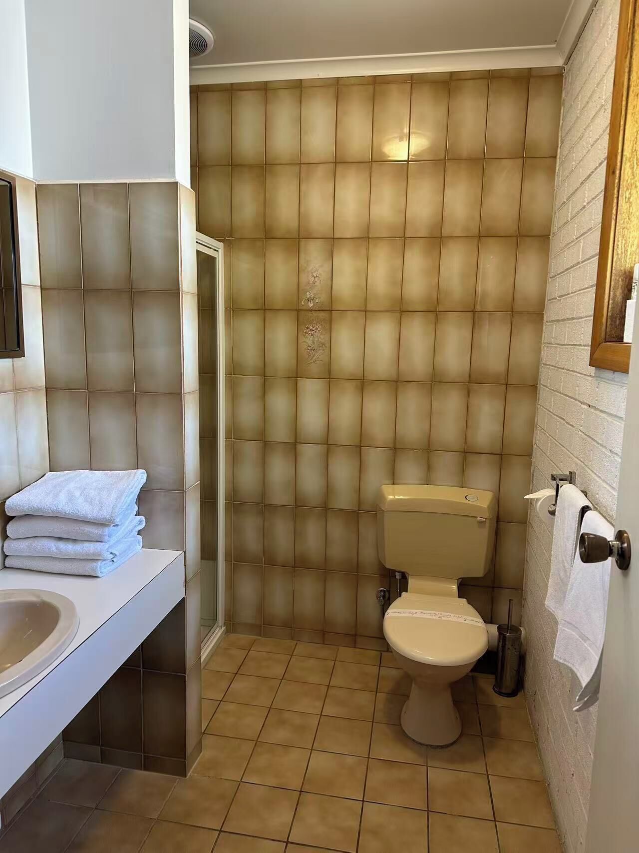 A bathroom with a toilet, sink, and towel stack.