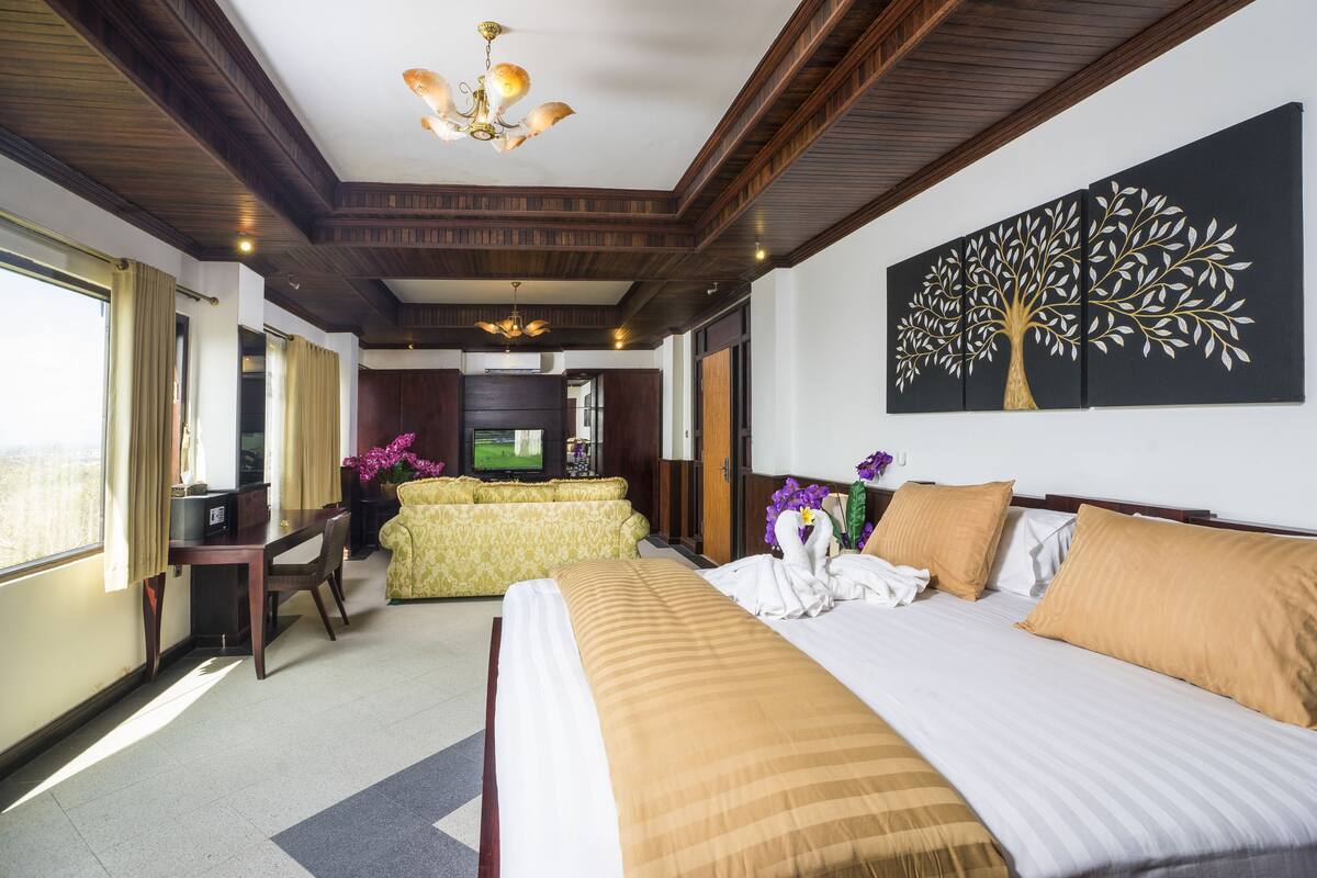 A hotel room with a large bed, a television, a desk, and a dining area.