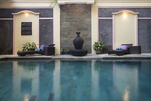 A pool area with lounge chairs and a large vase centerpiece.