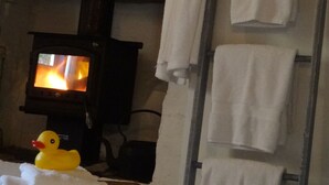 Ein Zimmer mit Kamin, ein weißer Bademantel hängt dort, ein Handtuchhalter mit Handtüchern und eine Quietscheente auf einem Handtuch.