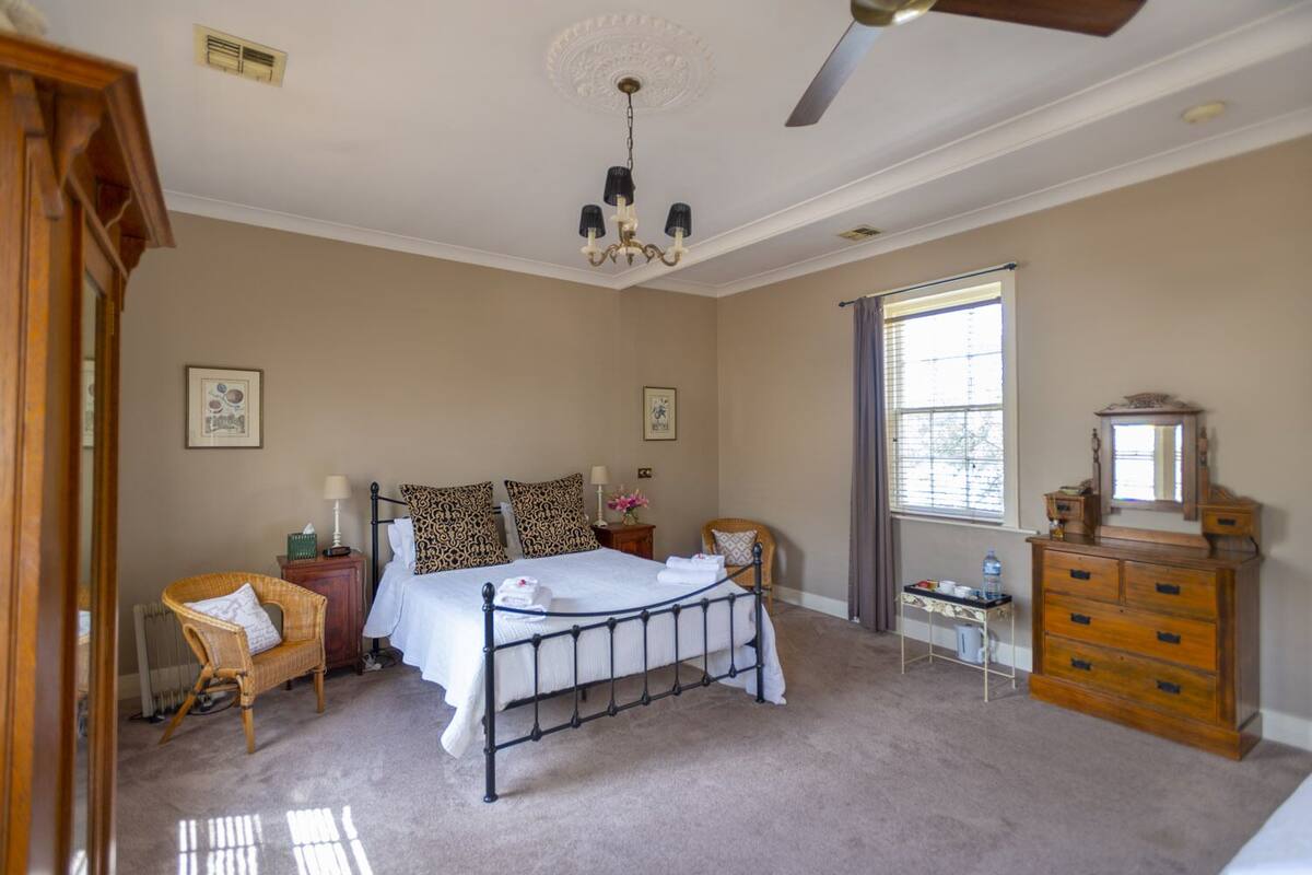 A bedroom with a bed, a dresser, a chair, a desk, and a window.