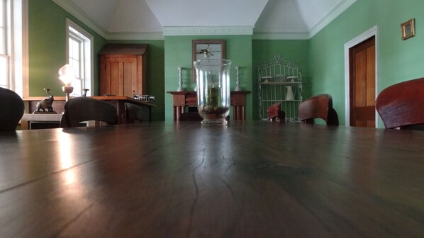 Una habitación amplia con piso de madera, un jarrón grande con piedras, un mueble de madera y una silla.