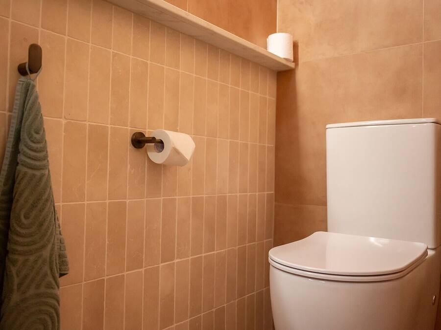 A bathroom with a toilet, a towel rack, and a toilet paper holder.
