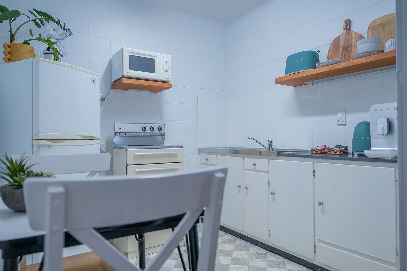 A compact kitchen with white cabinets, a microwave, a stove, and a sink.