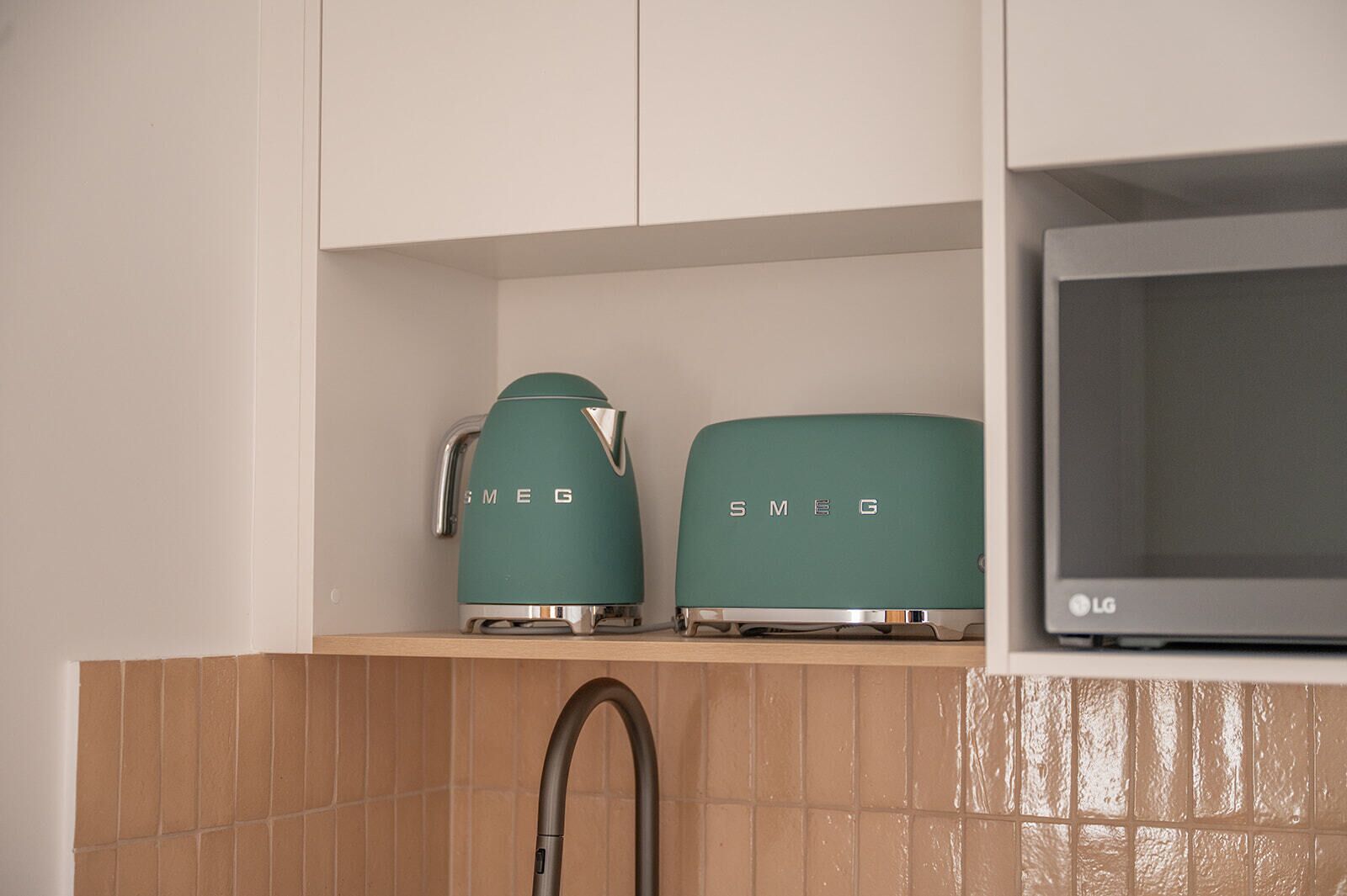A kitchen with two green appliances, a microwave, and a faucet.