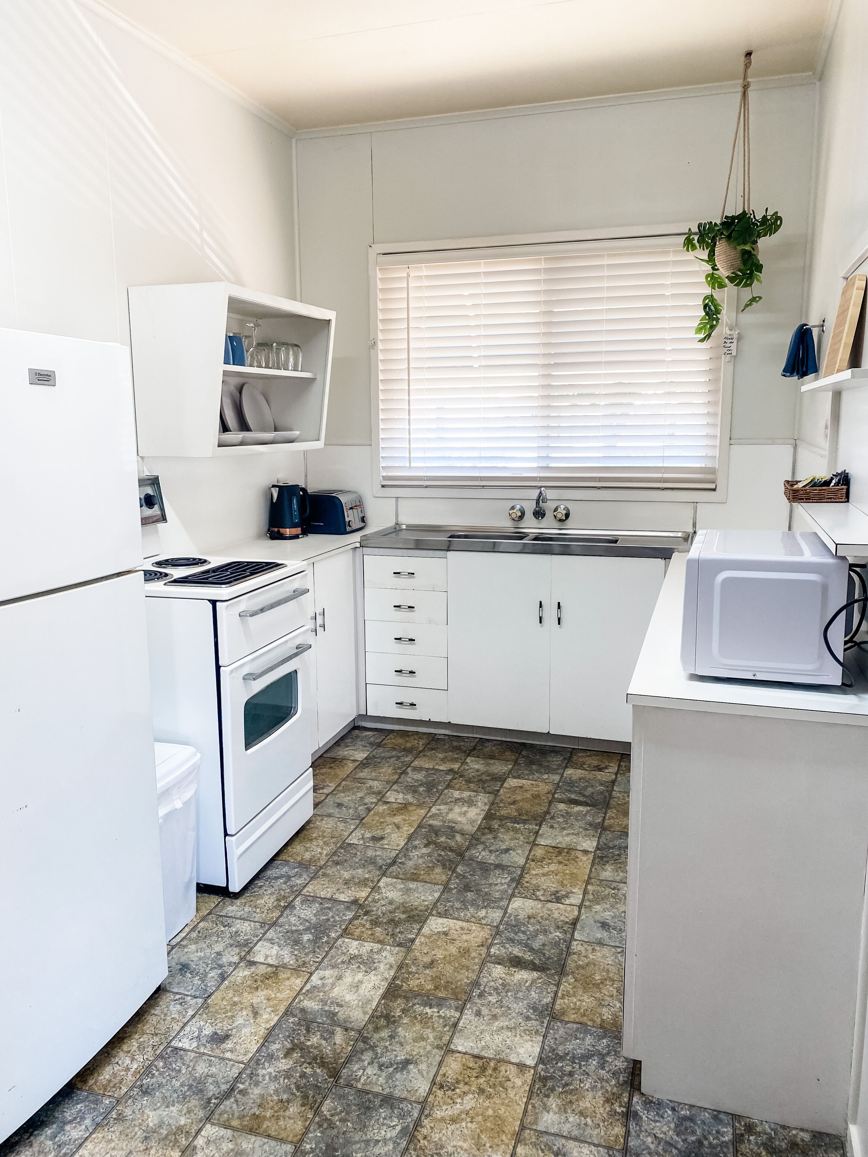 A compact kitchen with white cabinets, a built-in oven, a microwave, and a sink.