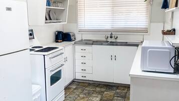 A compact kitchen with white cabinets, a built-in oven, a microwave, and a sink.