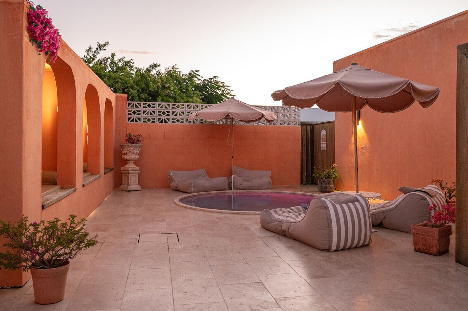 A courtyard with a pool, seating area, and umbrellas.